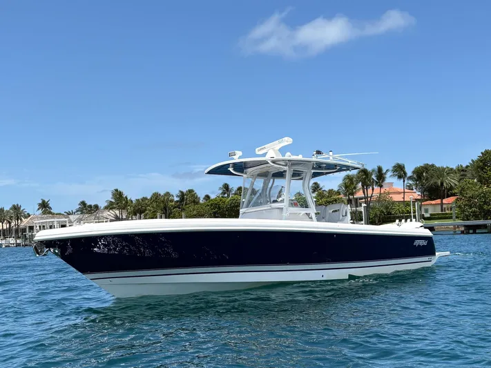 Agitator Yacht Photos Pics 2016 Intrepid 327 Center Console boat on clear blue water, with palm trees in the background.