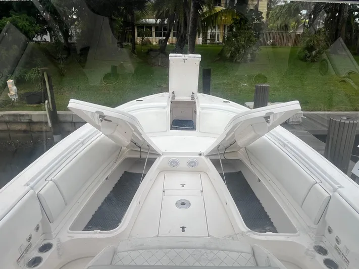Agitator Yacht Photos Pics 2016 Intrepid 327 Center Console boat with open storage compartments, docked near lush greenery.