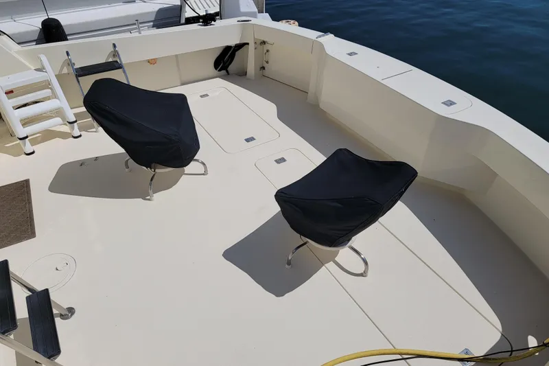 Southern Girl Yacht Photos Pics 1989 Hatteras Convertible boat deck with covered chairs and ladder, near water.