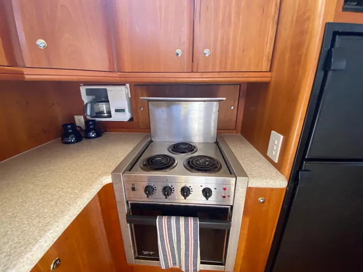 Aqua Holic Yacht Photos Pics 2002 Silverton 43 MY yacht kitchen with stove, coffee maker, and wooden cabinets.