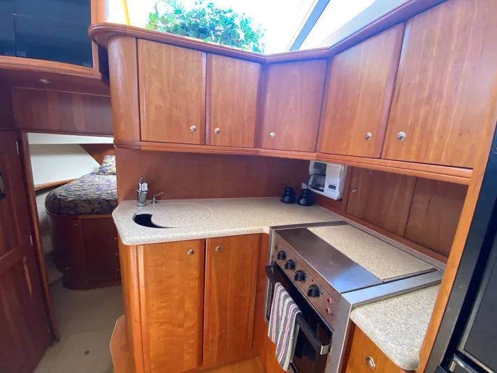 Aqua Holic Yacht Photos Pics 2002 Silverton 43 MY yacht kitchen with wood cabinets, stove, and sink.
