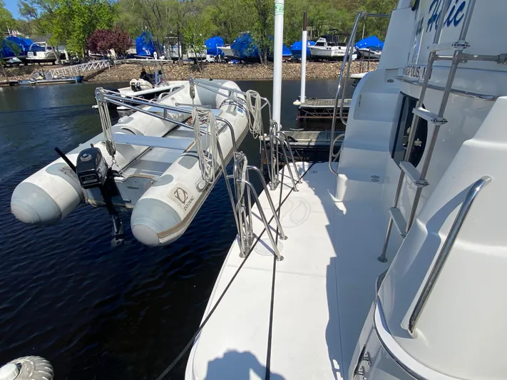 Aqua Holic Yacht Photos Pics 2002 Silverton 43 MY yacht with inflatable boat on davit system, docked by a marina.