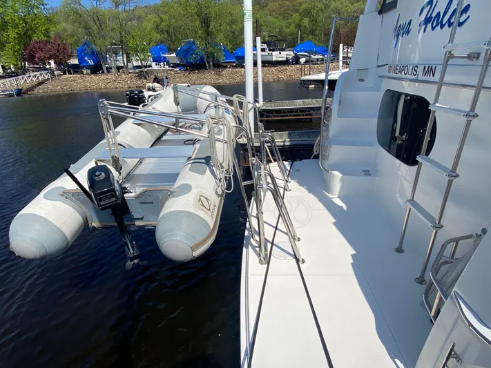 Aqua Holic Yacht Photos Pics 2002 Silverton 43 MY yacht with attached inflatable boat, docked in a scenic marina.