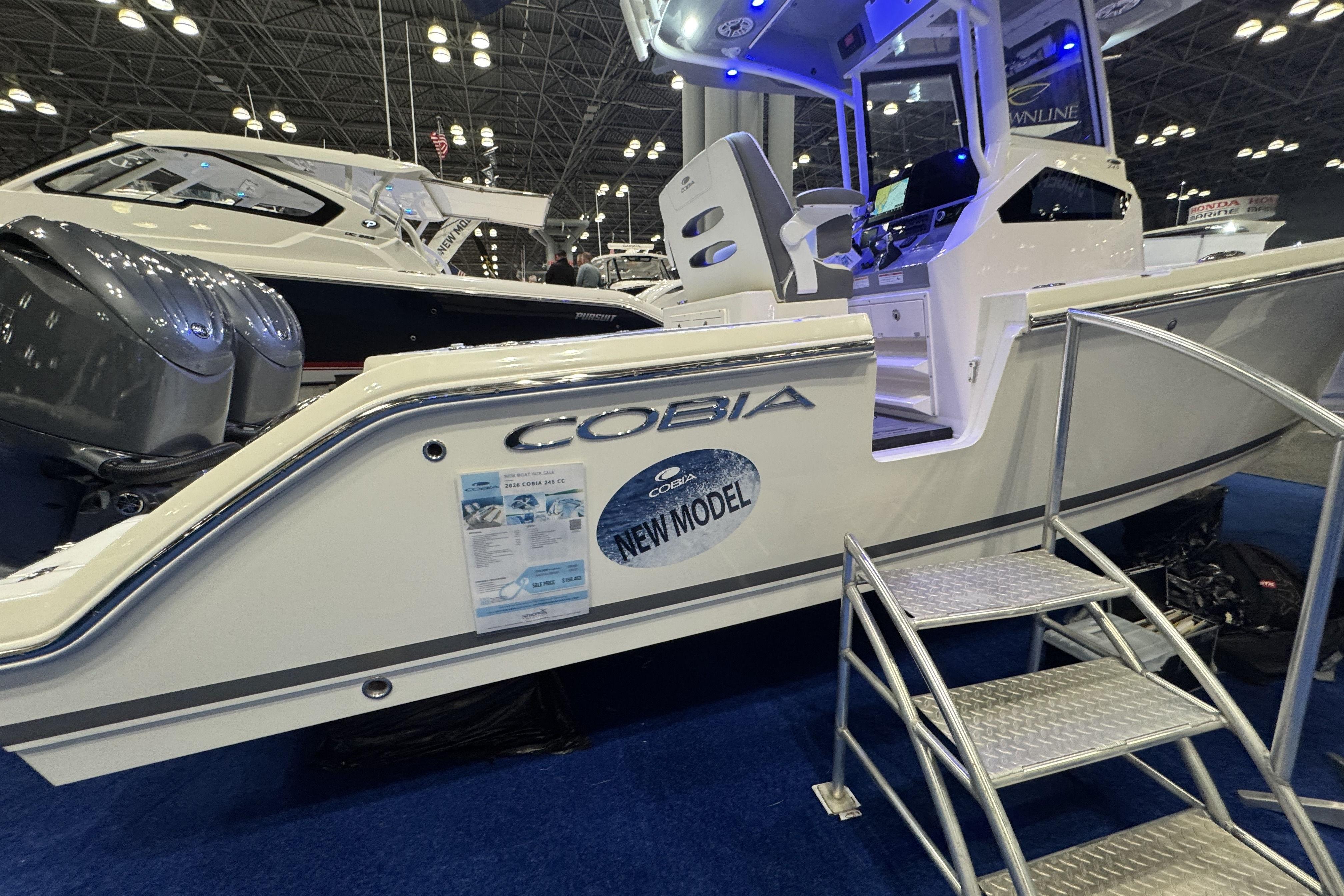2026 Cobia 245 Center Console boat displayed at an indoor exhibition with blue lighting.