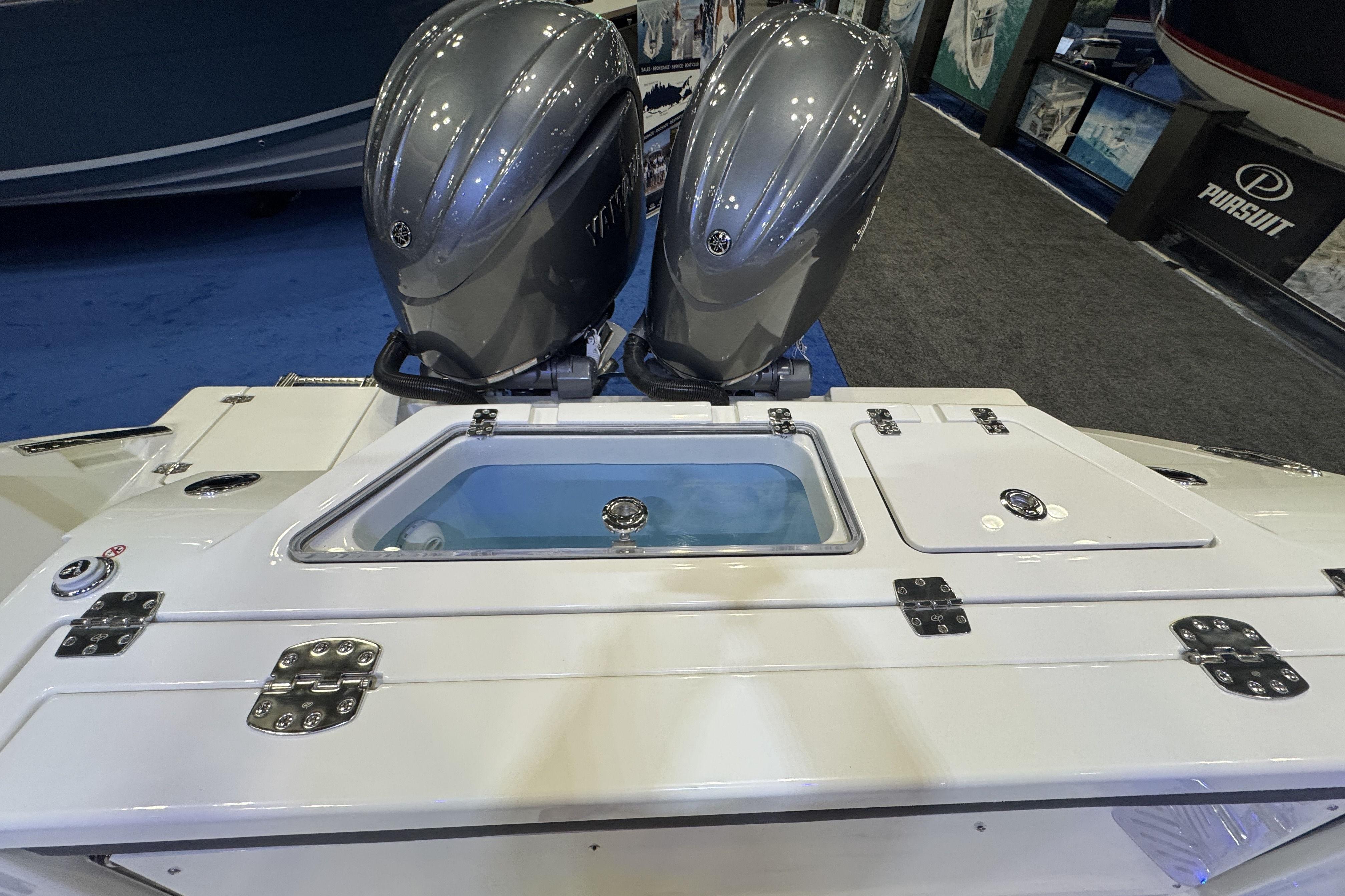 2026 Cobia 245 Center Console with dual outboard engines at a boat show display.