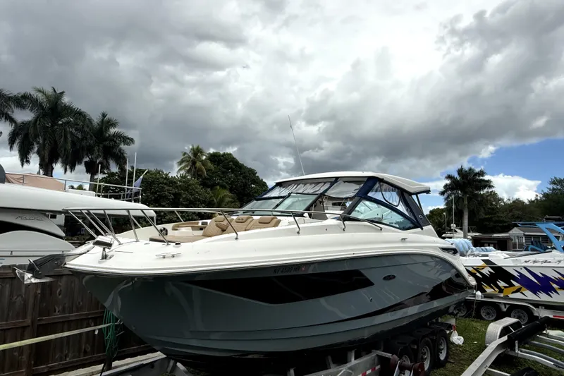  Yacht Photos Pics 2020 Sea Ray Sundancer 320 boat on trailer, under cloudy sky with palm trees.