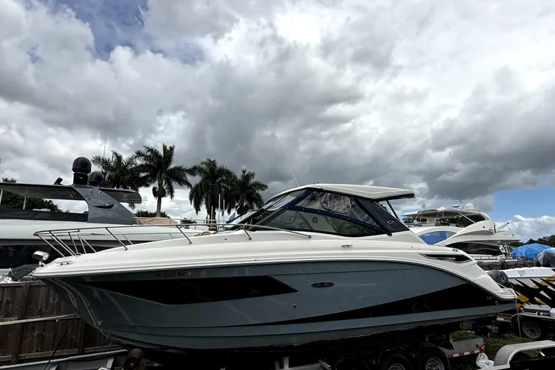  Yacht Photos Pics 2020 Sea Ray Sundancer 320 yacht on trailer, cloudy sky, palm trees in background.