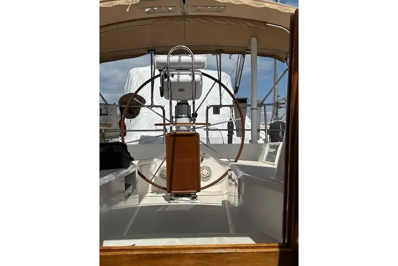 Serendipity II Yacht Photos Pics 1999 Sabre 452 sailboat cockpit with wooden wheel and canopy under clear sky.
