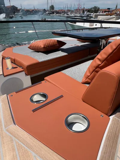  Yacht Photos Pics Luxurious 2025 Astondoa 677 Coupe yacht with elegant seating and cup holders, docked at a marina.