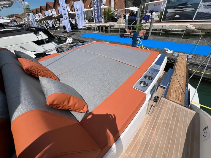  Yacht Photos Pics 2025 Astondoa 677 Coupe yacht with luxurious sunbathing deck and stylish cushions at a marina.