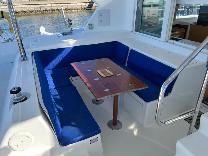 Sunbear Yacht Photos Pics Lagoon 420 yacht cockpit with blue cushioned seating and wooden table, 2008 model.