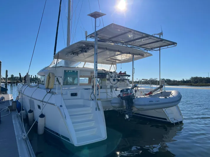 Sunbear Yacht Photos Pics 2008 Lagoon 420 catamaran docked, featuring solar panels and a dinghy, under clear blue sky.