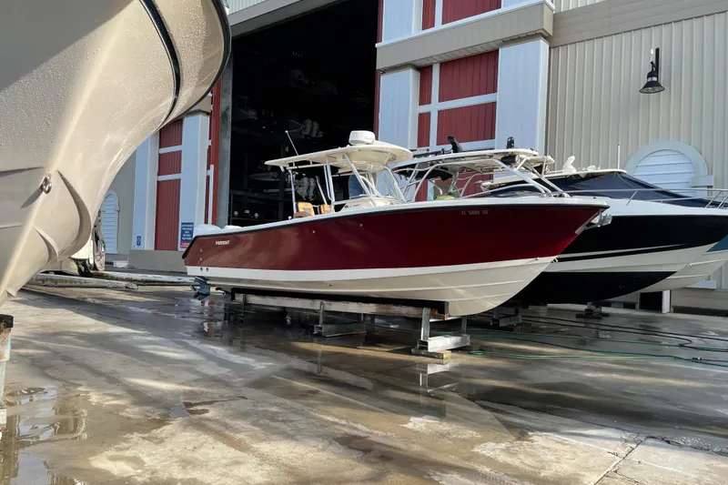  Yacht Photos Pics 2010 Pursuit C 280 Center Console boat in storage, red hull, parked indoors.