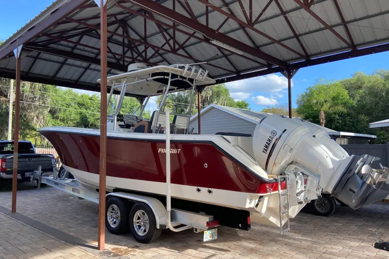  Yacht Photos Pics 2010 Pursuit C 280 Center Console boat on trailer under metal canopy.