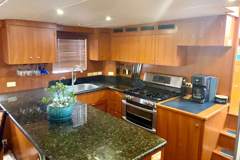 El Sueno Yacht Photos Pics Luxurious kitchen in 1998 Grand Alaskan 60 Pilothouse yacht with granite countertops and wooden cabinetry.