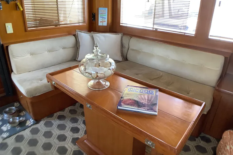 El Sueno Yacht Photos Pics Cozy interior of 1998 Grand Alaskan 60 Pilothouse with cushioned seating and wooden table.