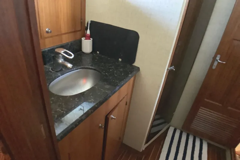 El Sueno Yacht Photos Pics 1998 Grand Alaskan 60 Pilothouse bathroom with granite countertop and wooden cabinetry.