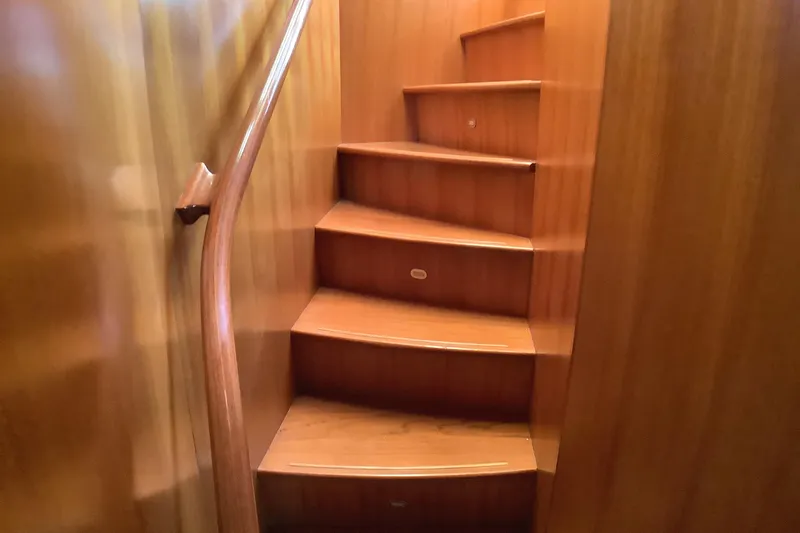 El Sueno Yacht Photos Pics Wooden staircase inside 1998 Grand Alaskan 60 Pilothouse yacht, featuring curved handrail.