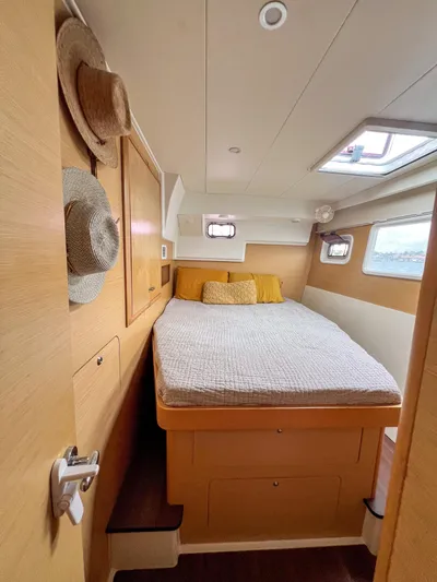 Dao And Out Yacht Photos Pics Cozy bedroom interior of 2011 Lagoon 400 catamaran with natural wood finish and porthole windows.