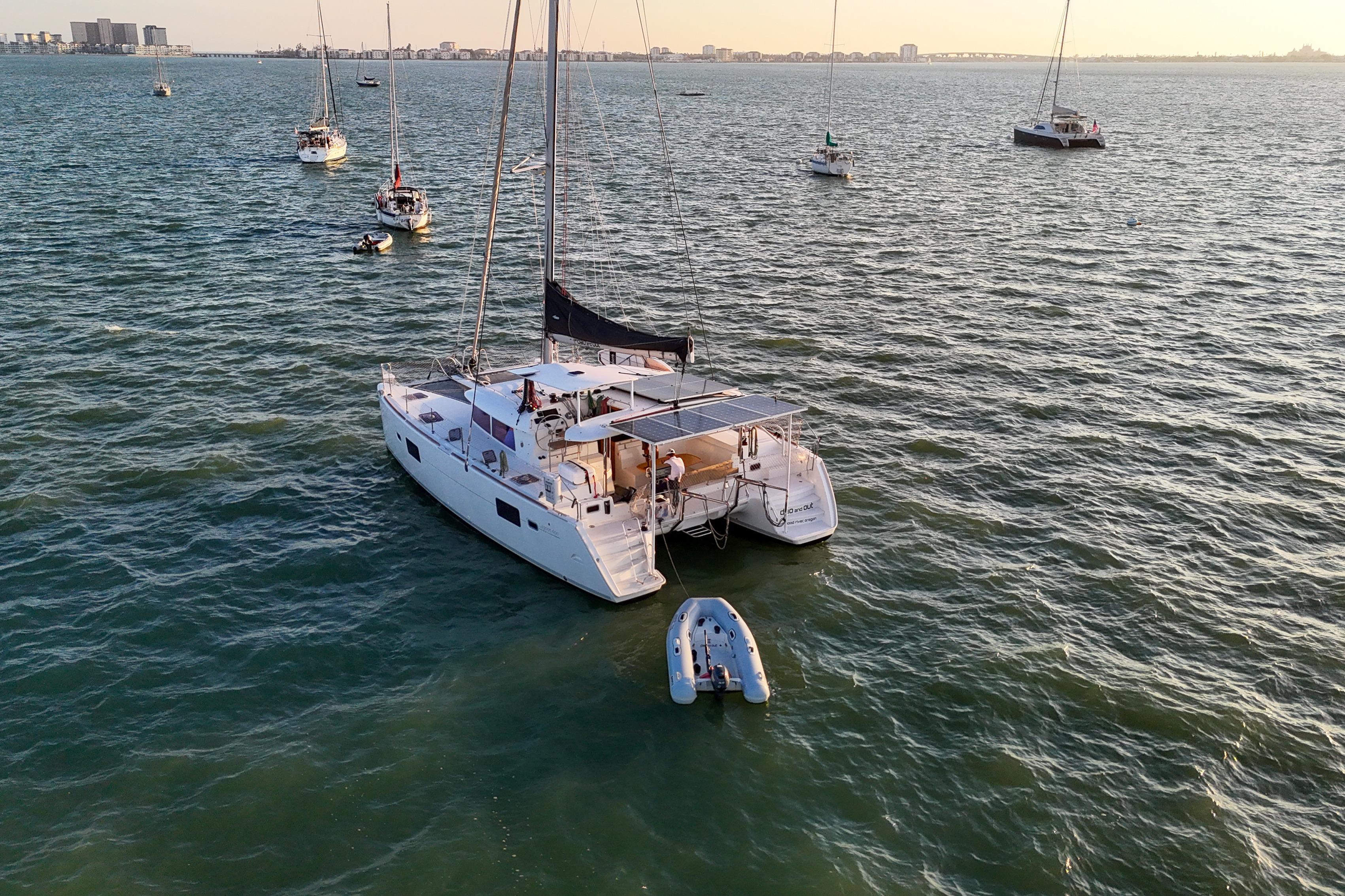 Lagoon 400 catamaran from 2011 anchored in a serene bay with other sailboats.