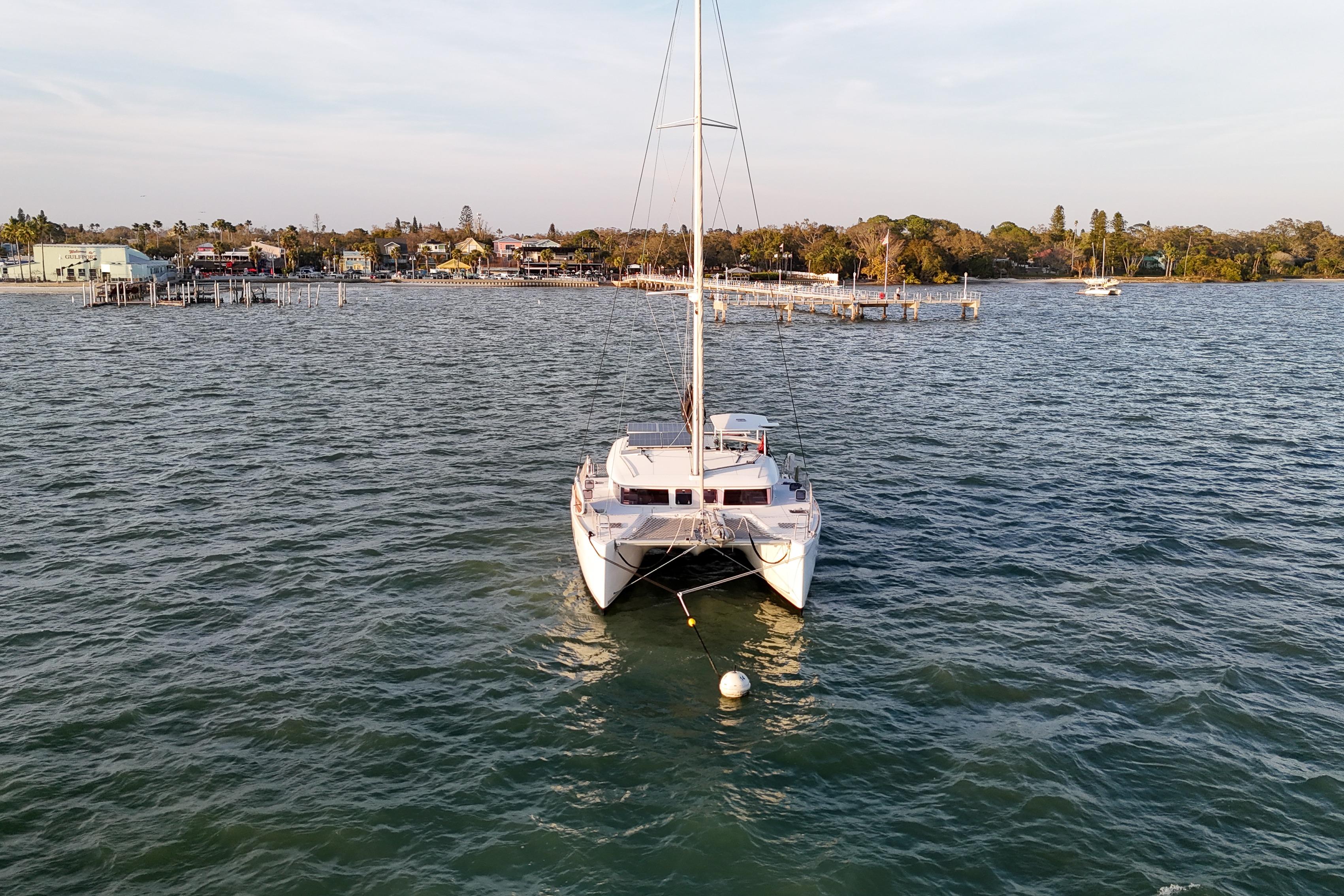 2011 Lagoon 400 catamaran anchored in calm waters near a coastal town.