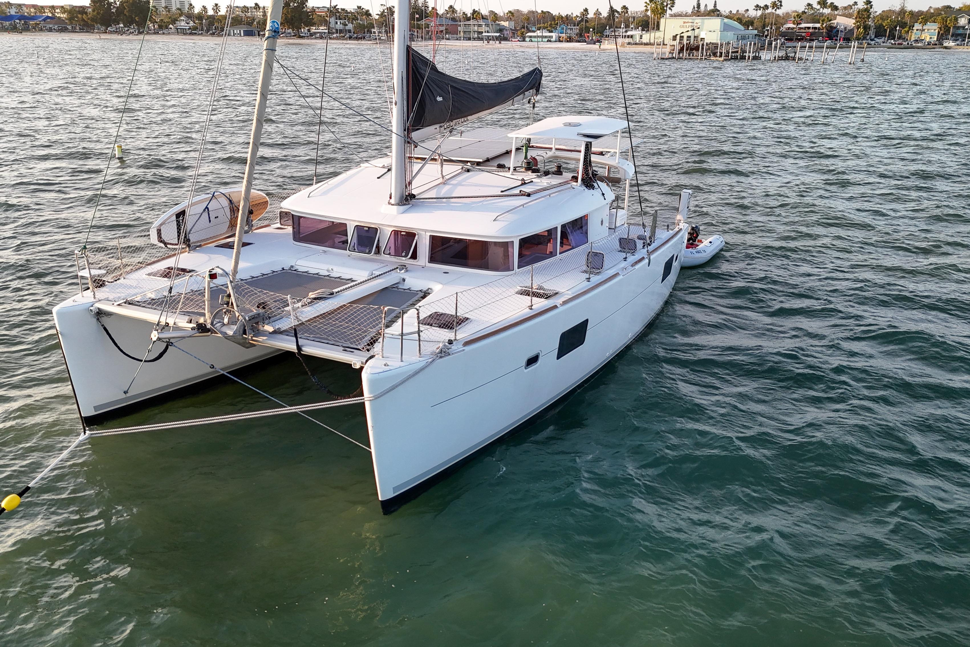 2011 Lagoon 400 catamaran sailing on calm waters near a coastal town.