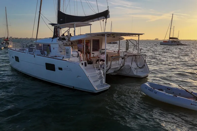 Dao And Out Yacht Photos Pics 2011 Lagoon 400 catamaran anchored at sunset with inflatable dinghy nearby.