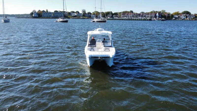 Reel'y Busy Yacht Photos Pics 2020 World Cat 280 DC x boat on calm water with sailboats in the background.