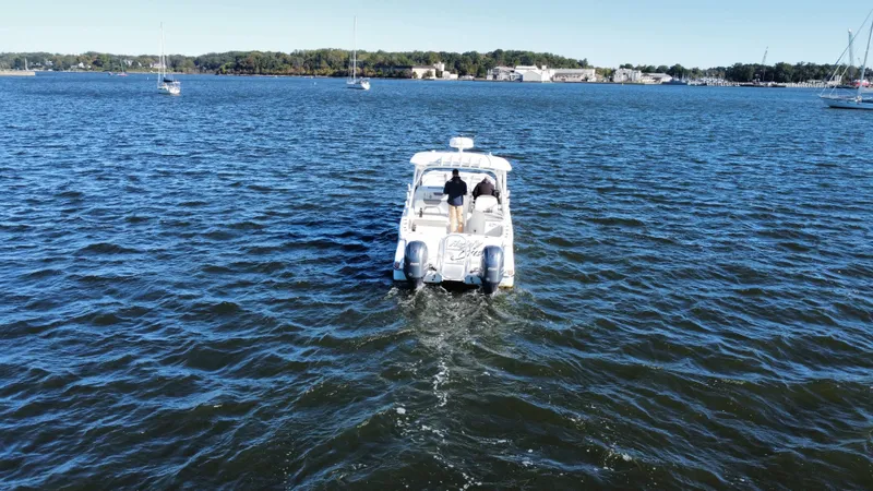 Reel'y Busy Yacht Photos Pics 2020 World Cat 280 DC x cruising on a serene lake with distant shoreline.