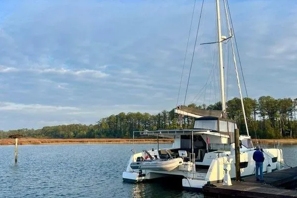 Amihan Yacht Photos Pics 2023 Fountaine Pajot Isla 40 catamaran docked on a serene lake with trees.