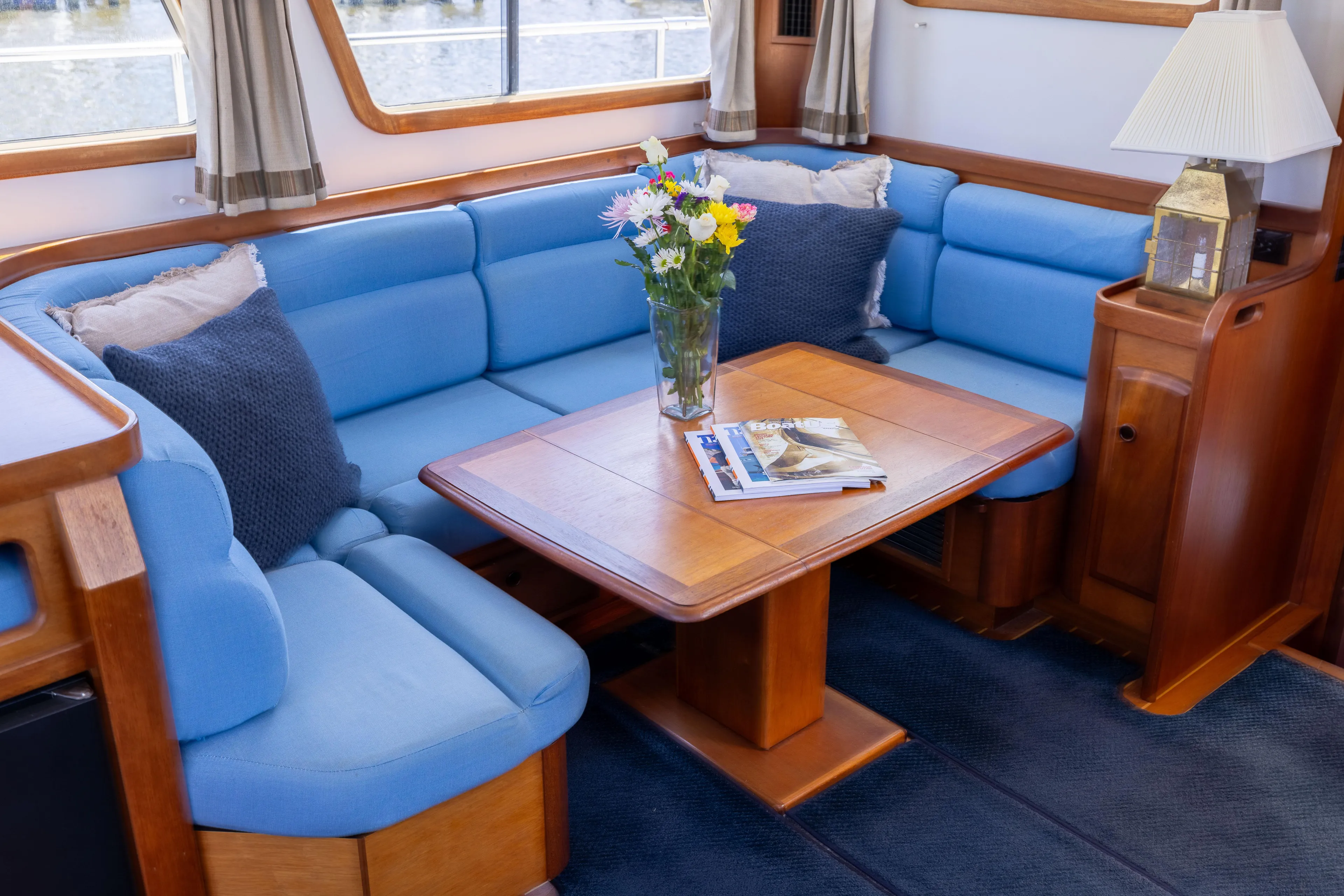 Nellie Yacht Photos Pics Interior of 1998 Sabreline 47 Aft Cabin Trawler with blue seating and wooden table.