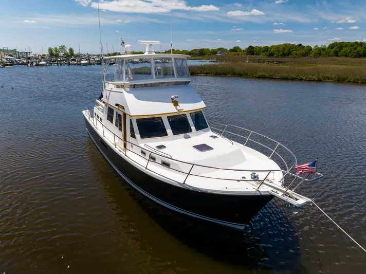 Nellie Yacht Photos Pics 1998 Sabreline 47 Aft Cabin Trawler cruising on a calm river under a clear blue sky.