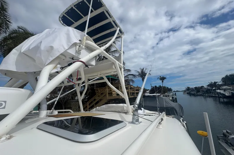 Yacht Photos Pics 2014 Pursuit OS 345 Offshore boat docked by a scenic canal under a cloudy sky.
