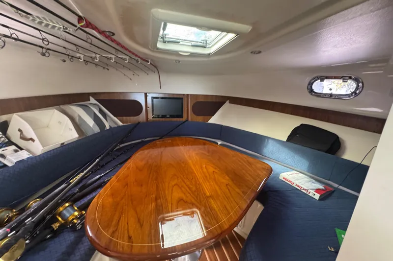  Yacht Photos Pics 2014 Pursuit OS 345 Offshore cabin with fishing rods, table, and seating area.
