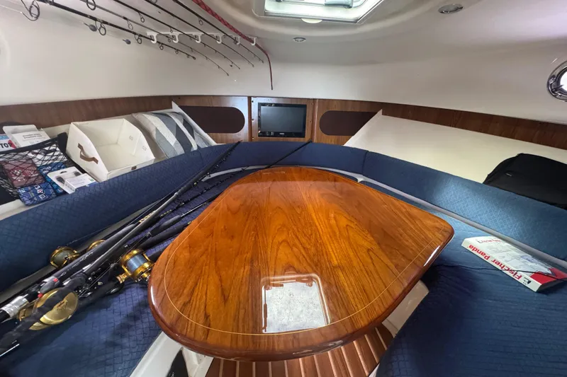  Yacht Photos Pics 2014 Pursuit OS 345 Offshore cabin with fishing rods, wooden table, and blue seating.