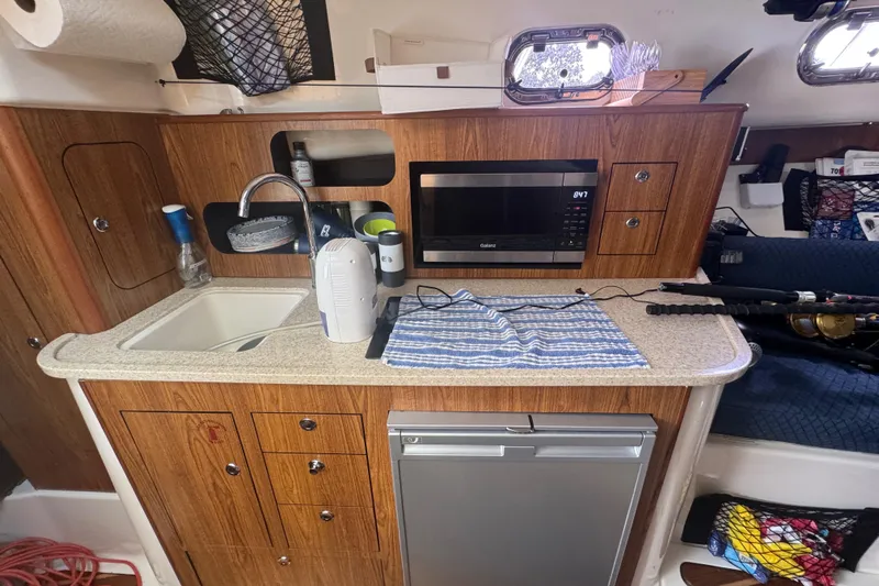  Yacht Photos Pics 2014 Pursuit OS 345 Offshore boat interior with kitchenette, sink, microwave, and storage cabinets.