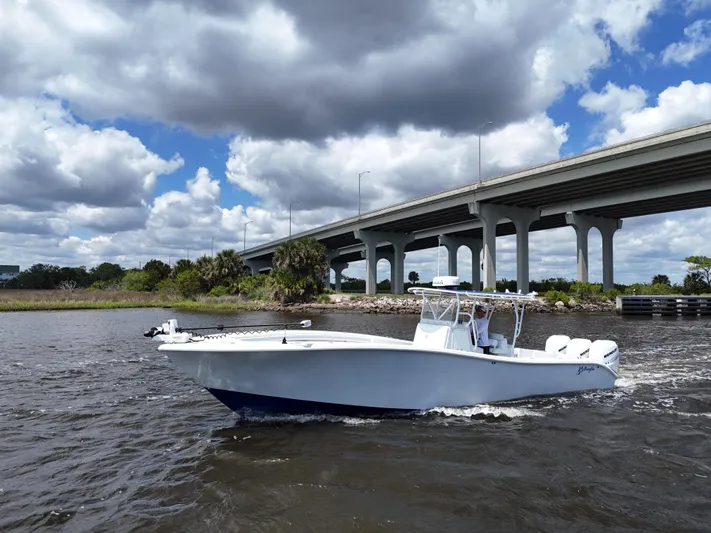  Yacht Photos Pics 2003 Yellowfin 36 Offshore boat cruising under a cloudy sky near a bridge.