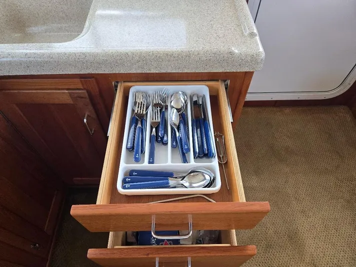 Ecola Yacht Photos Pics Cutlery drawer in 2005 American Tug 34 Pilothouse kitchen, featuring blue-handled utensils.