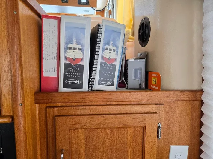 Ecola Yacht Photos Pics Manuals and documents on a wooden shelf in a 2005 American Tug 34 Pilothouse.