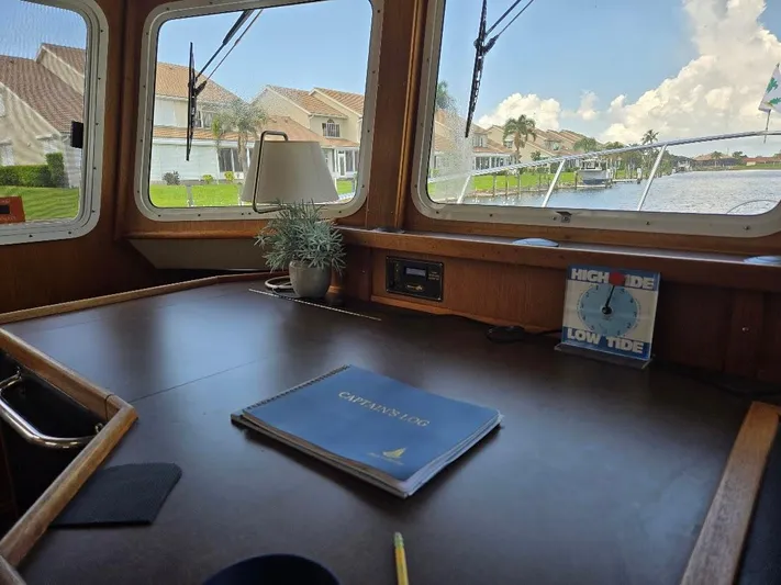 Ecola Yacht Photos Pics Pilothouse interior of 2005 American Tug 34, featuring a captain's log and tide clock.