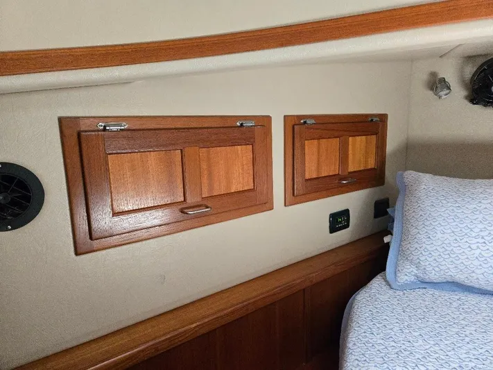 Ecola Yacht Photos Pics Interior of 2005 American Tug 34 Pilothouse with wooden cabinets and cozy bedding.