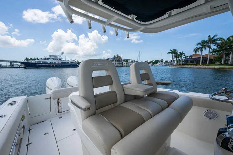 Ducky's Dinghy Yacht Photos Pics 2020 Boston Whaler 330 Outrage boat interior with luxurious seating, docked by waterfront homes.