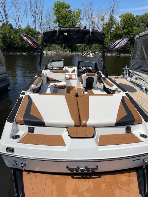 2021 Axis T23 boat with sleek design, brown and white seating, docked on a sunny day.