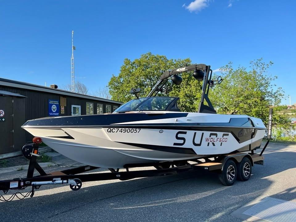 2021 Axis T23 boat on trailer, parked outdoors under clear blue sky.