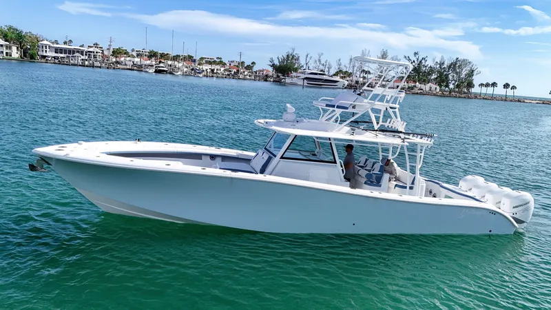  Yacht Photos Pics 2023 Yellowfin 42 boat cruising on clear blue water near a coastal town.