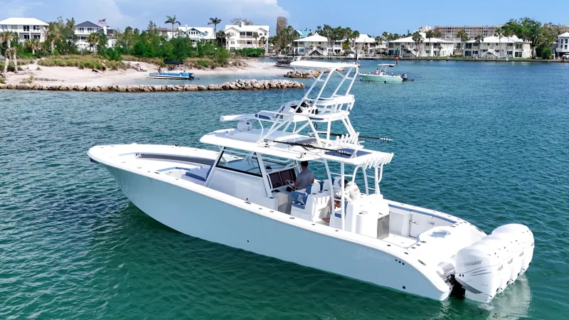  Yacht Photos Pics 2023 Yellowfin 42 boat cruising in clear blue waters near a coastal town.