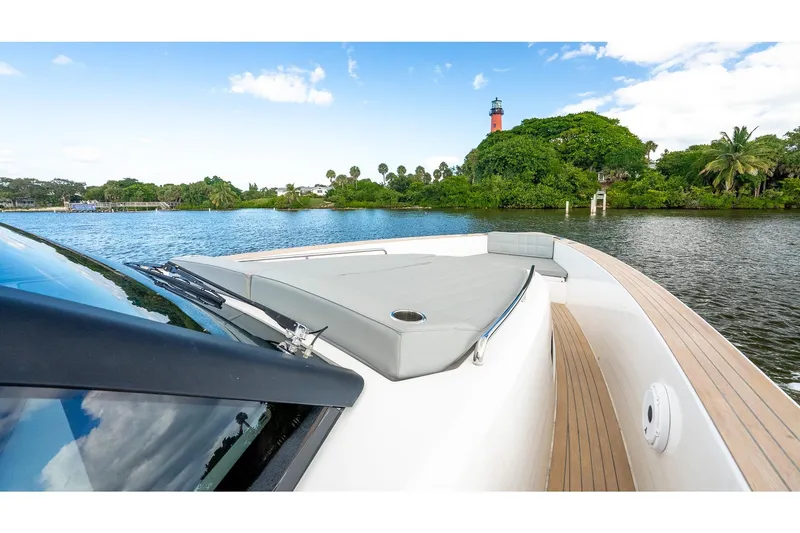  Yacht Photos Pics 2024 Pardo Yachts 43 cruising on a scenic river with lush greenery and a lighthouse.