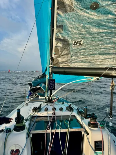 Sails Up Yacht Photos Pics 2022 Beneteau First 27 sailboat on open water, featuring vibrant blue sails.
