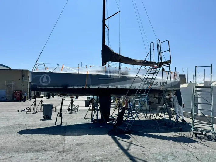 Sails Up Yacht Photos Pics 2022 Beneteau First 27 sailboat on dry dock, surrounded by maintenance equipment.