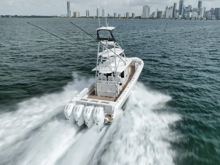 Yacht Photos Pics 2024 Contender 44 ST boat speeding on water with city skyline in background.